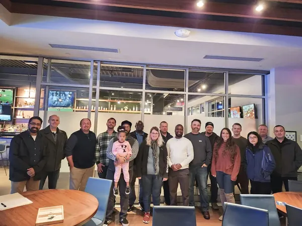 About twenty chapter members standing together for a group photo at an evening meetup