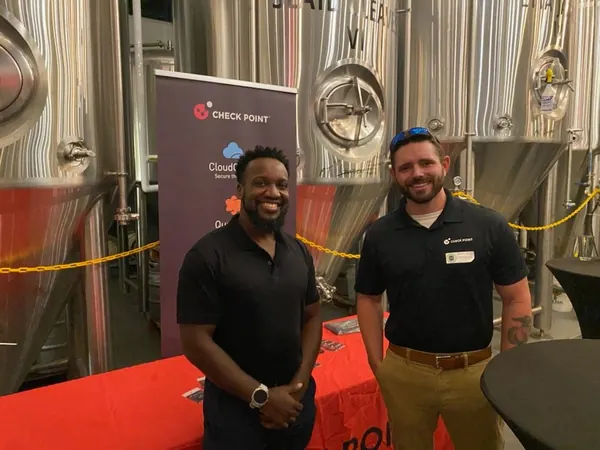 Two members standing in front of sponsor banners at a brewery
